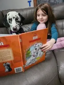 a young girl reading to a certified service dog